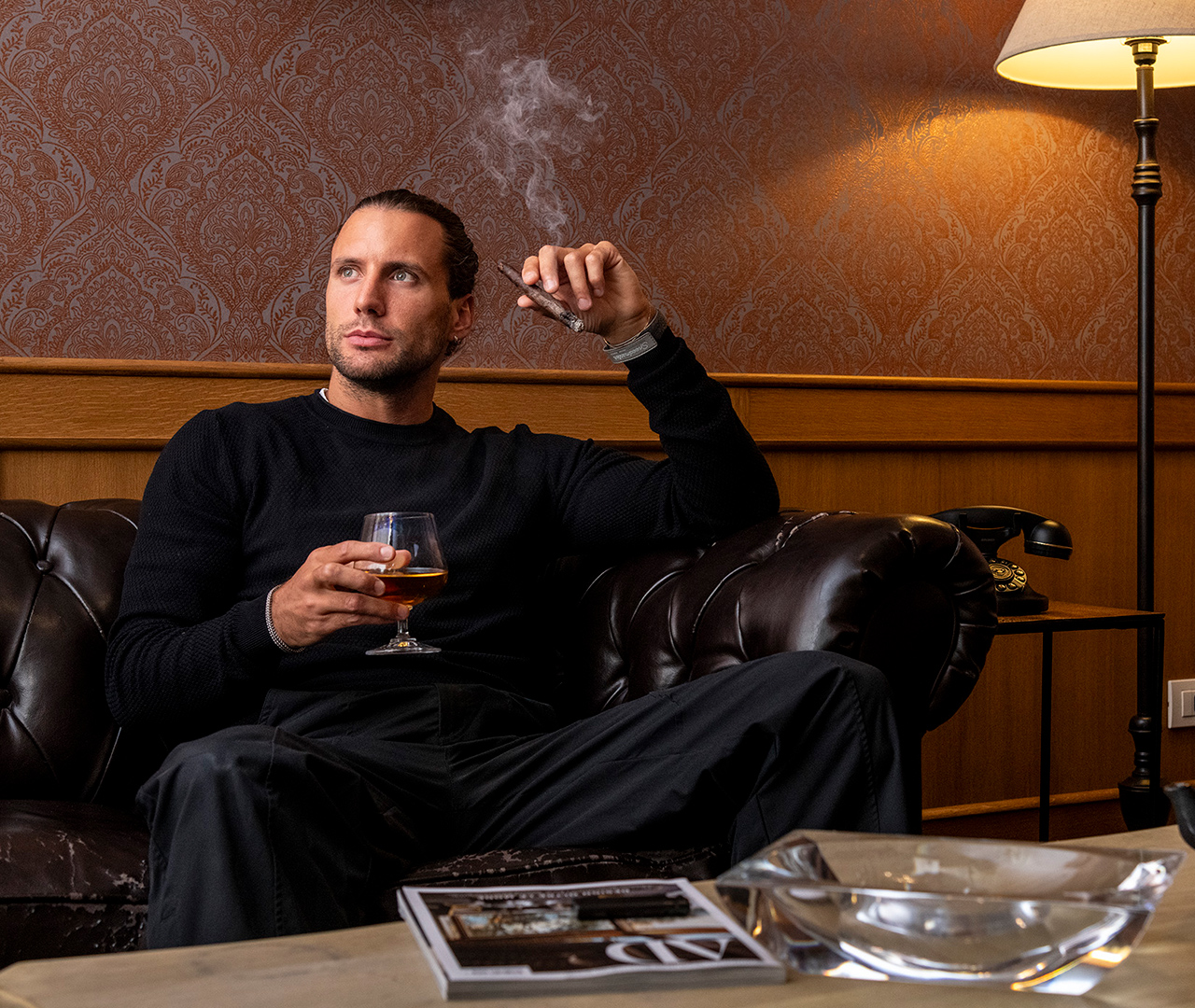 Cigar Room con luci soffuse e un ragazzo che si rilassa con sigaro e drink