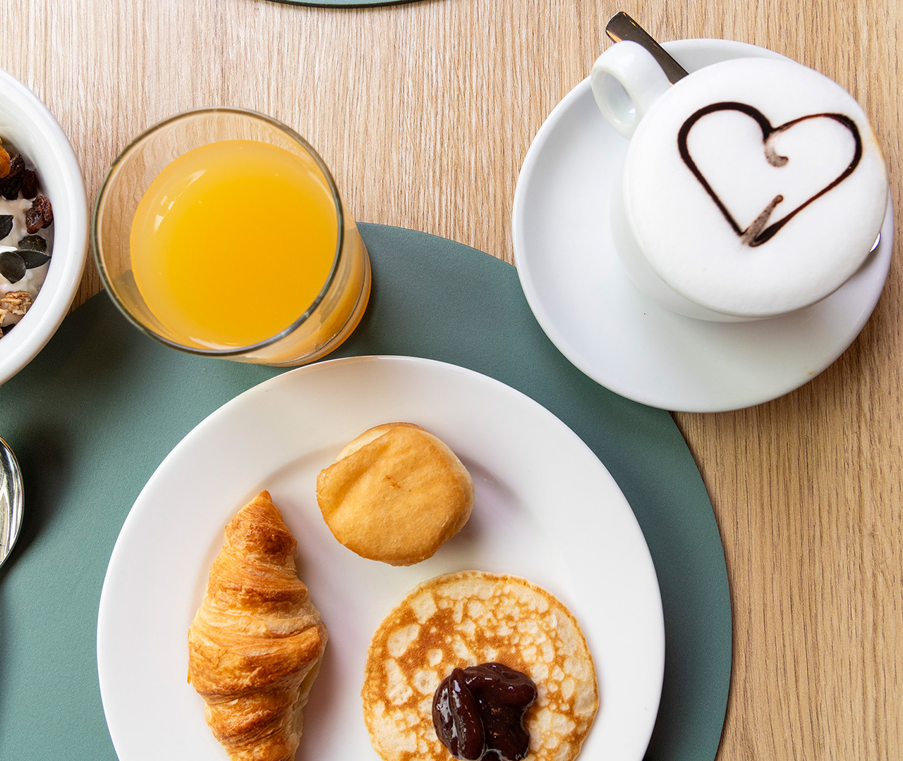 La nostra ricca colazione a buffet: un piatto con pancake e croissant, con un cappuccino e una spremuta