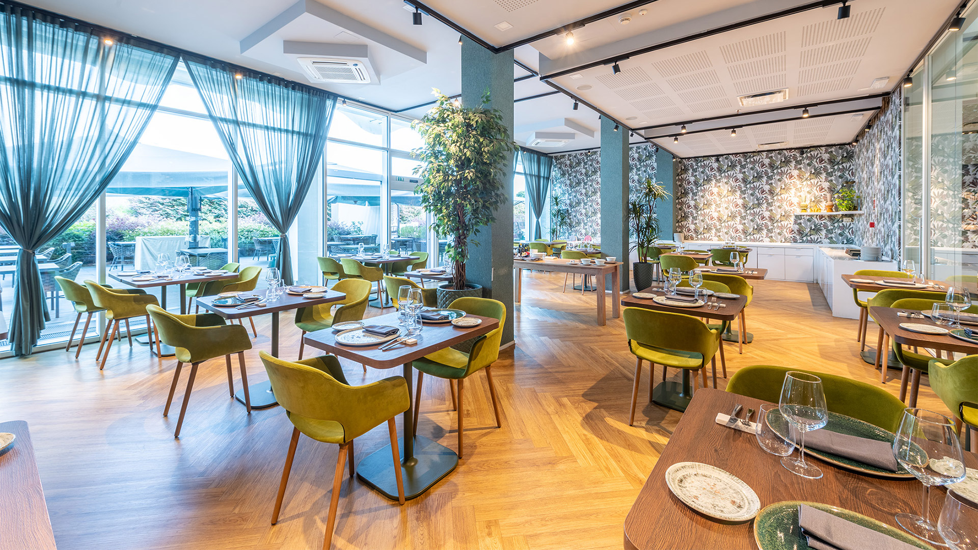 Luminosa sala del Bloom Restaurant al Moom Hotel, con tavoli apparecchiati, parquet e ampie vetrate che si aprono sul giardino