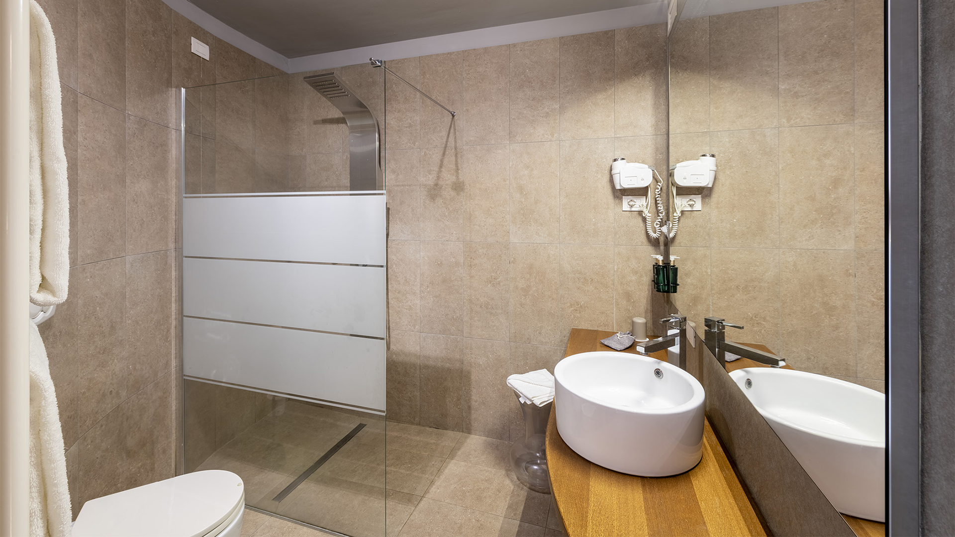 Lussuoso bagno della camera Deluxe: pareti beige chiaro, luce naturale, lavabo bianco e doccia aperta trasparente
