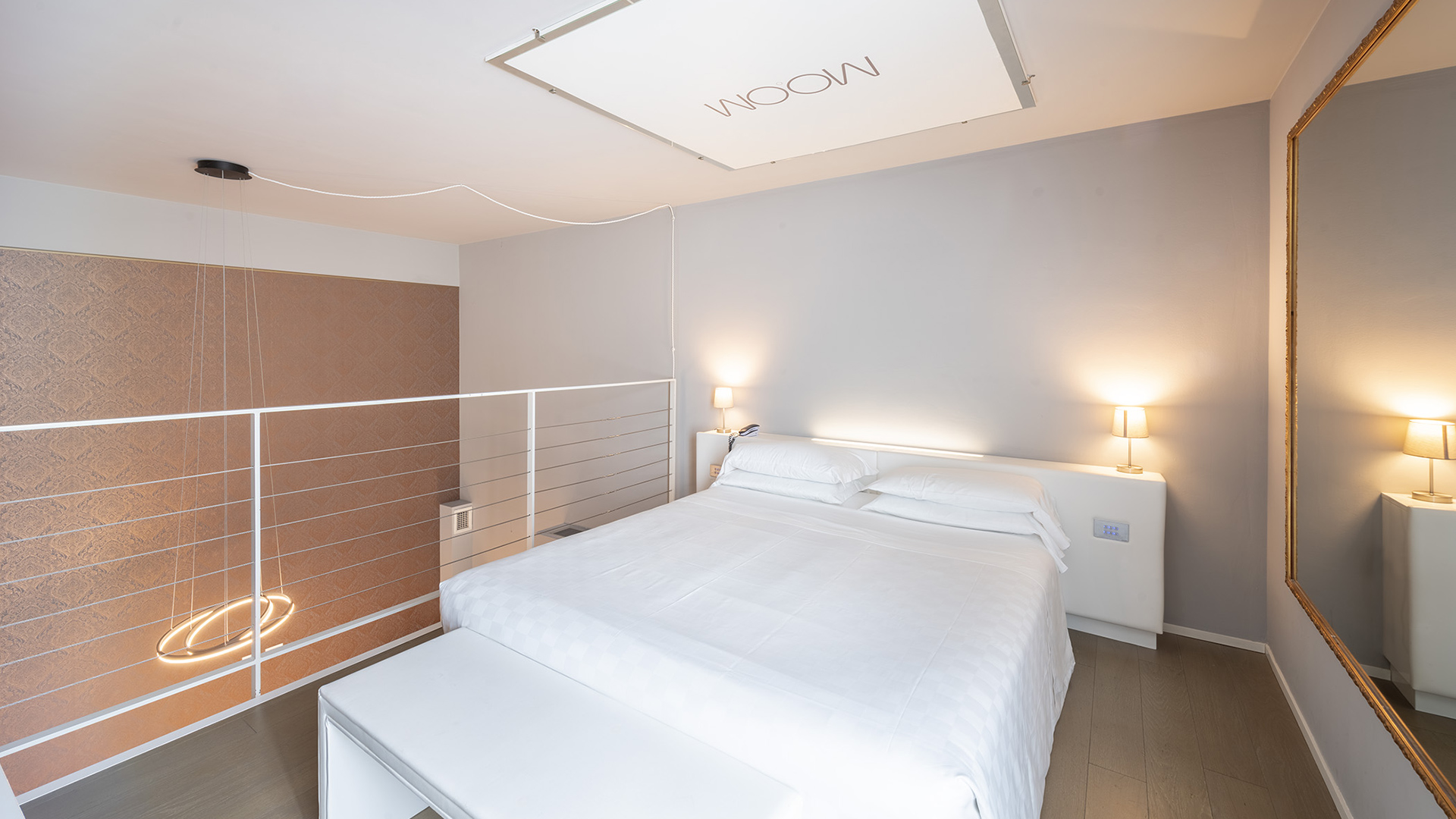 Luminosa e raffinata junior suite deluxe a due livelli con ampia finestra, balcone interno e vista su alberi